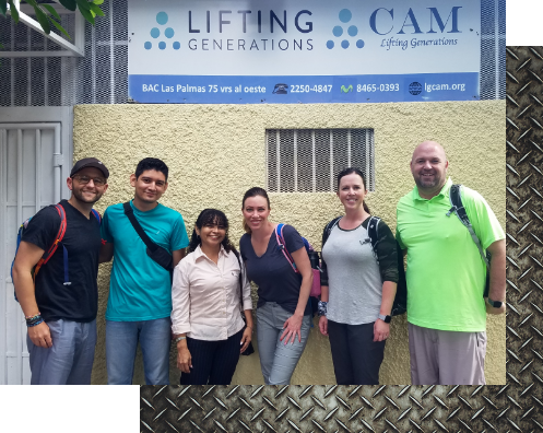Bryce and Dustin posing with friends in front of a Lifting Generations sign