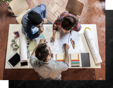 Top view of coworkers looking over apartment pans on a desk